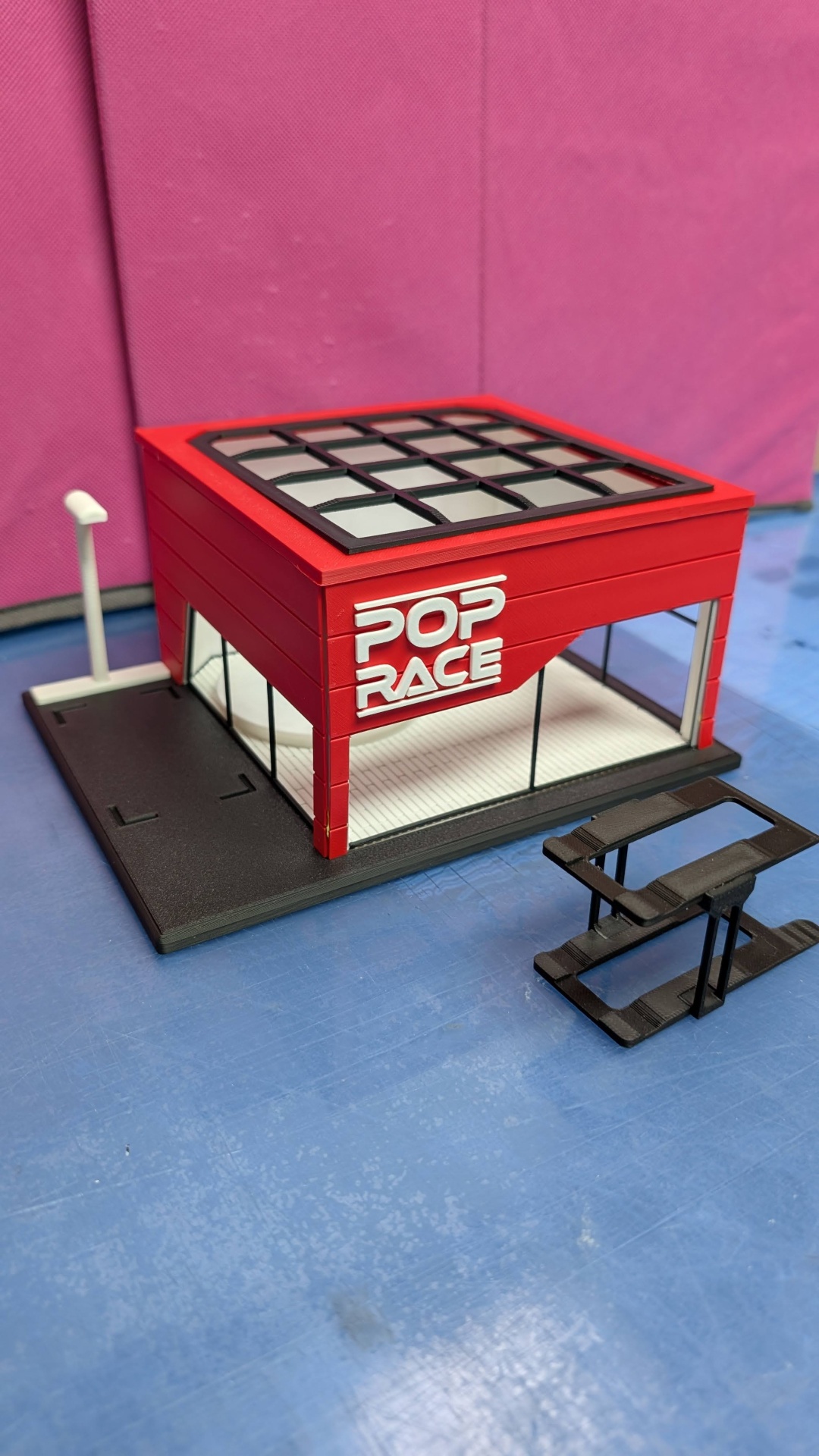 Miniatura de edifício vermelho com texto POP RACE em branco e janelas de vidro