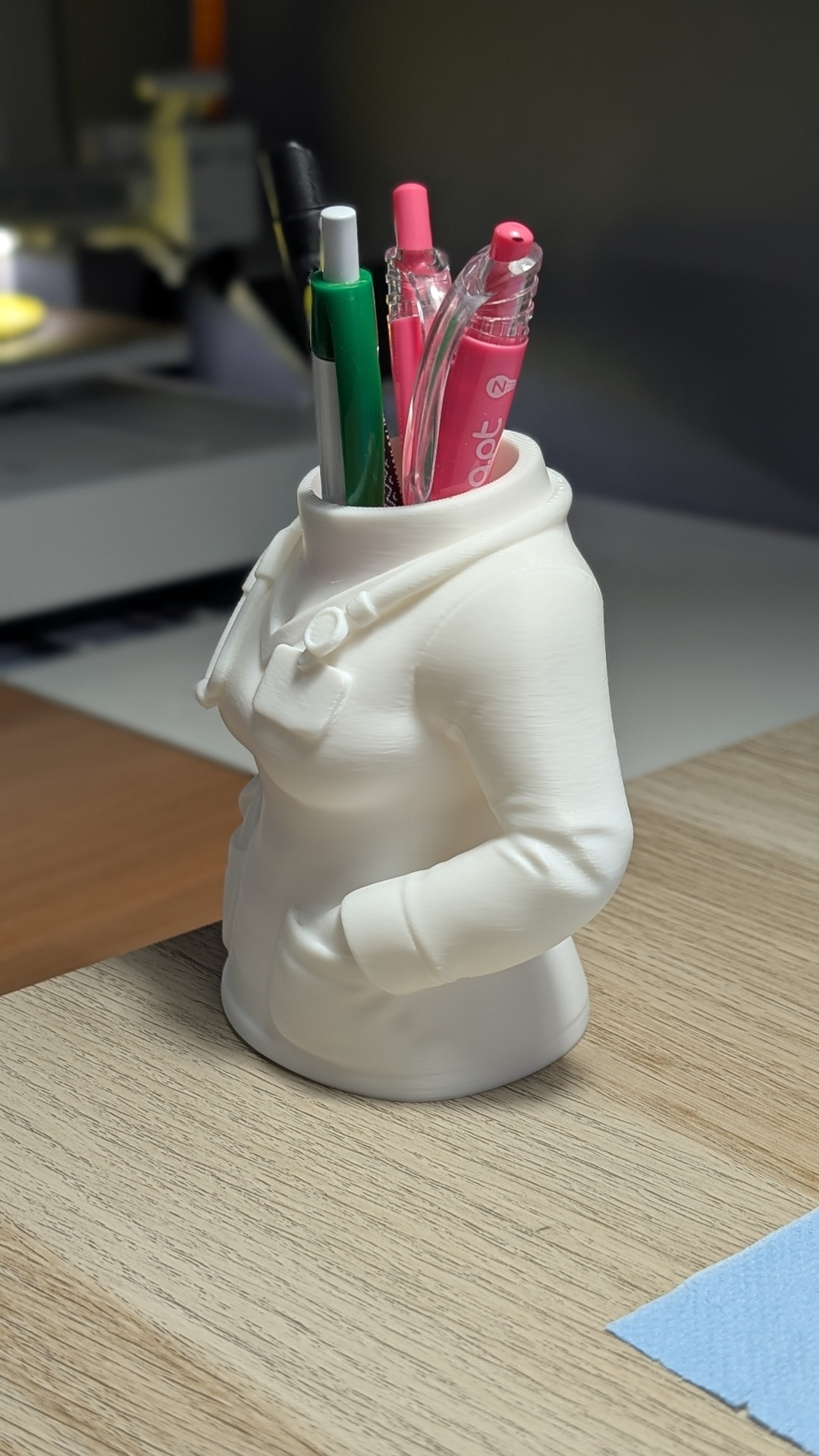 Suporte para canetas em forma de torso branco com canetas coloridas.