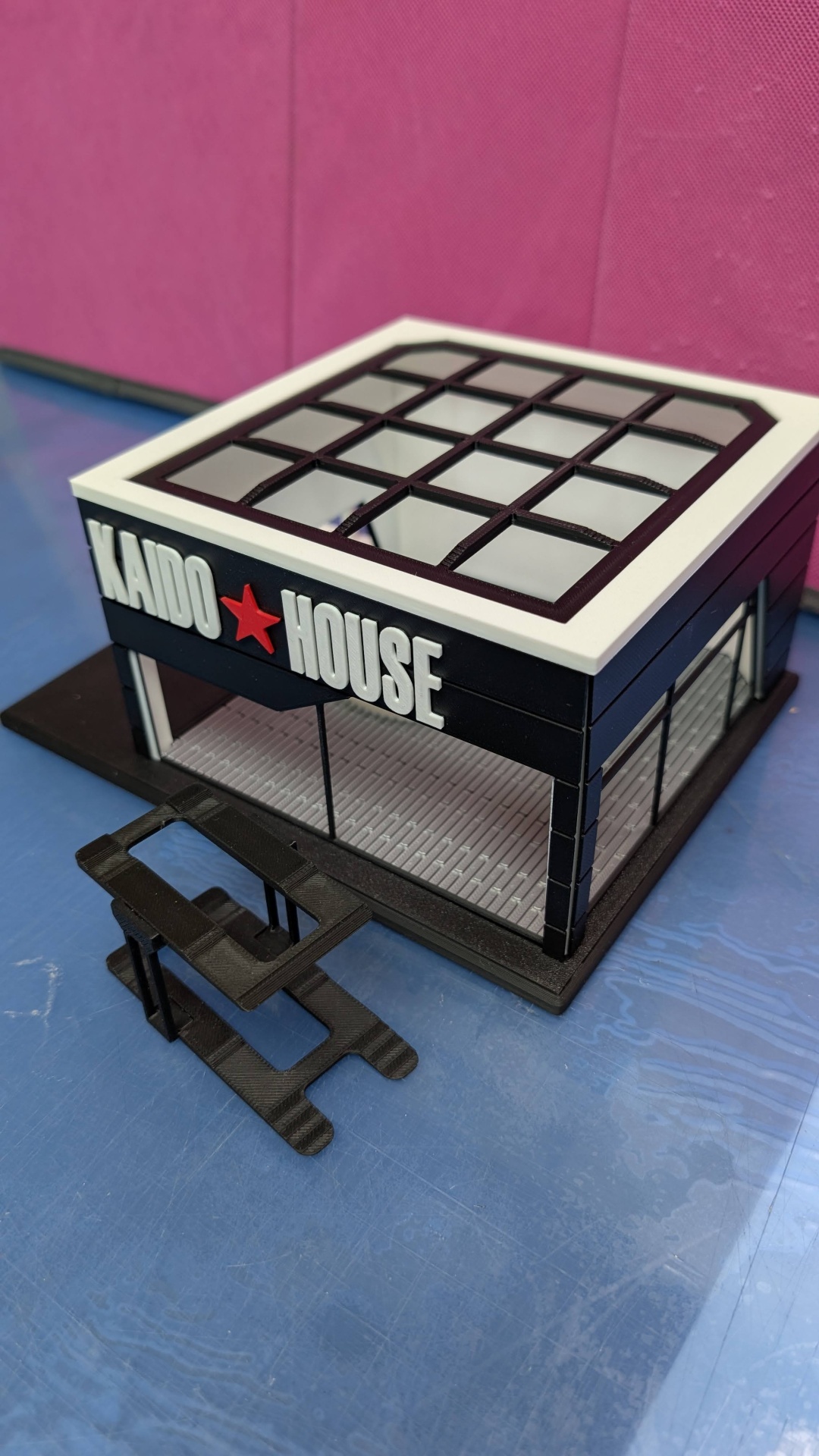 Miniatura de edifício com placa KAIDO HOUSE e estrutura em plástico preto e branco