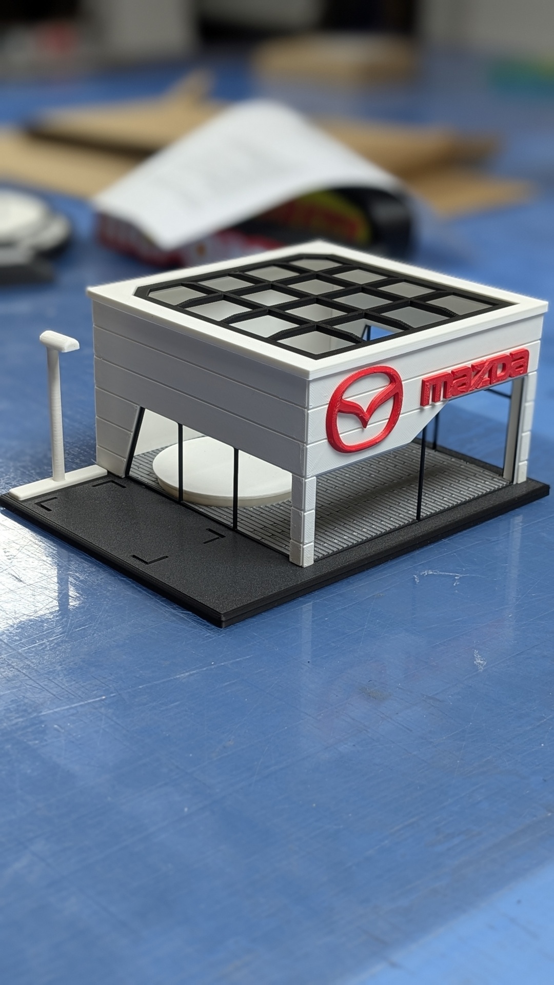 Miniatura de edifício com logo Mazda em branco e vermelho