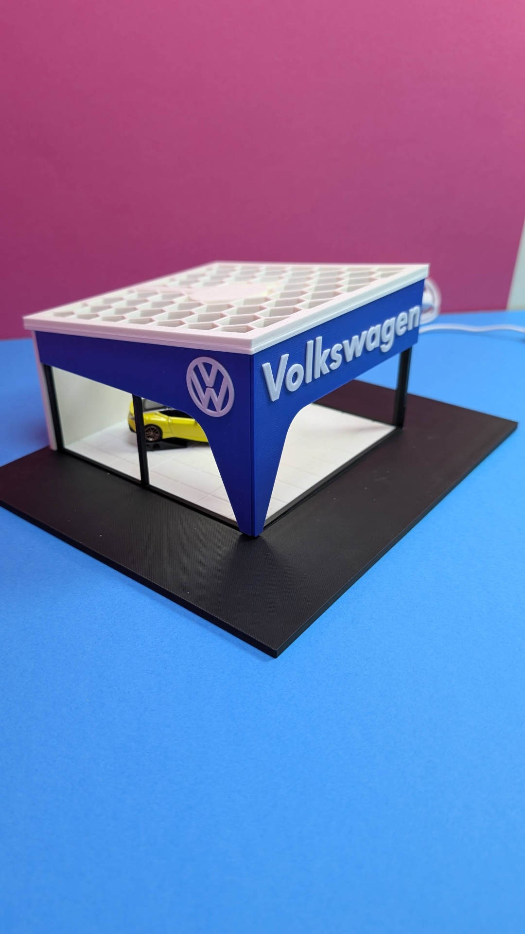 Miniatura de loja Volkswagen azul e branca com carro amarelo no interior