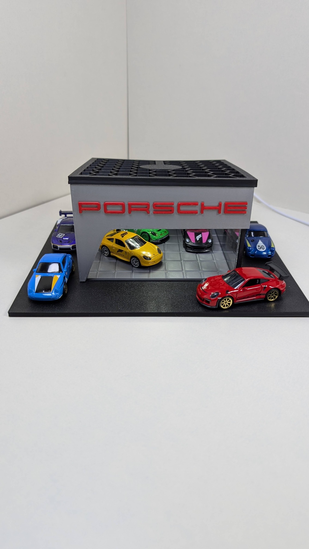 Miniatura de garagem Porsche cinzenta com carros miniatura coloridos