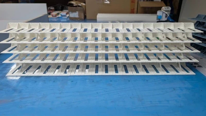 Estrutura branca de plástico com tiras e ranhuras em superfície azul.