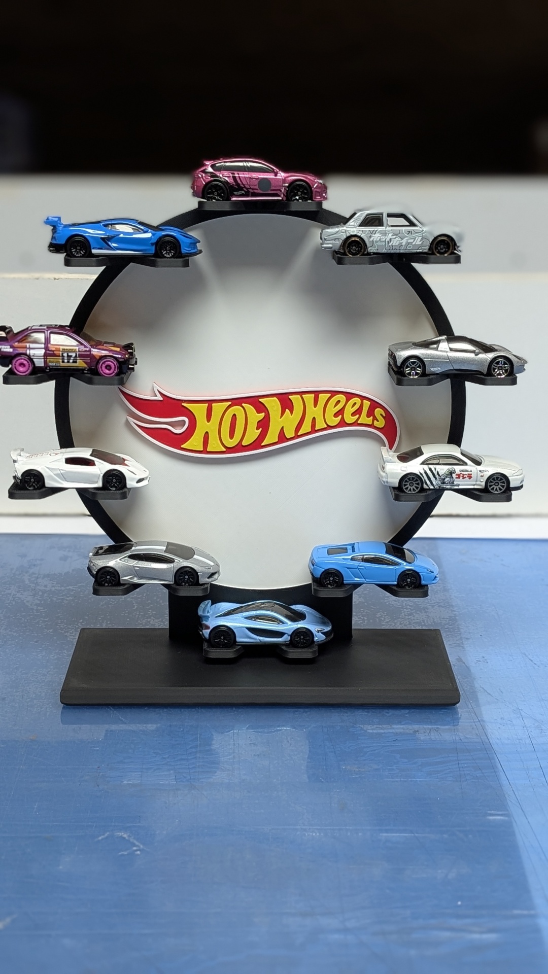 Conjunto de carros Hot Wheels em miniatura expostos num suporte circular com logótipo Hot Wheels.