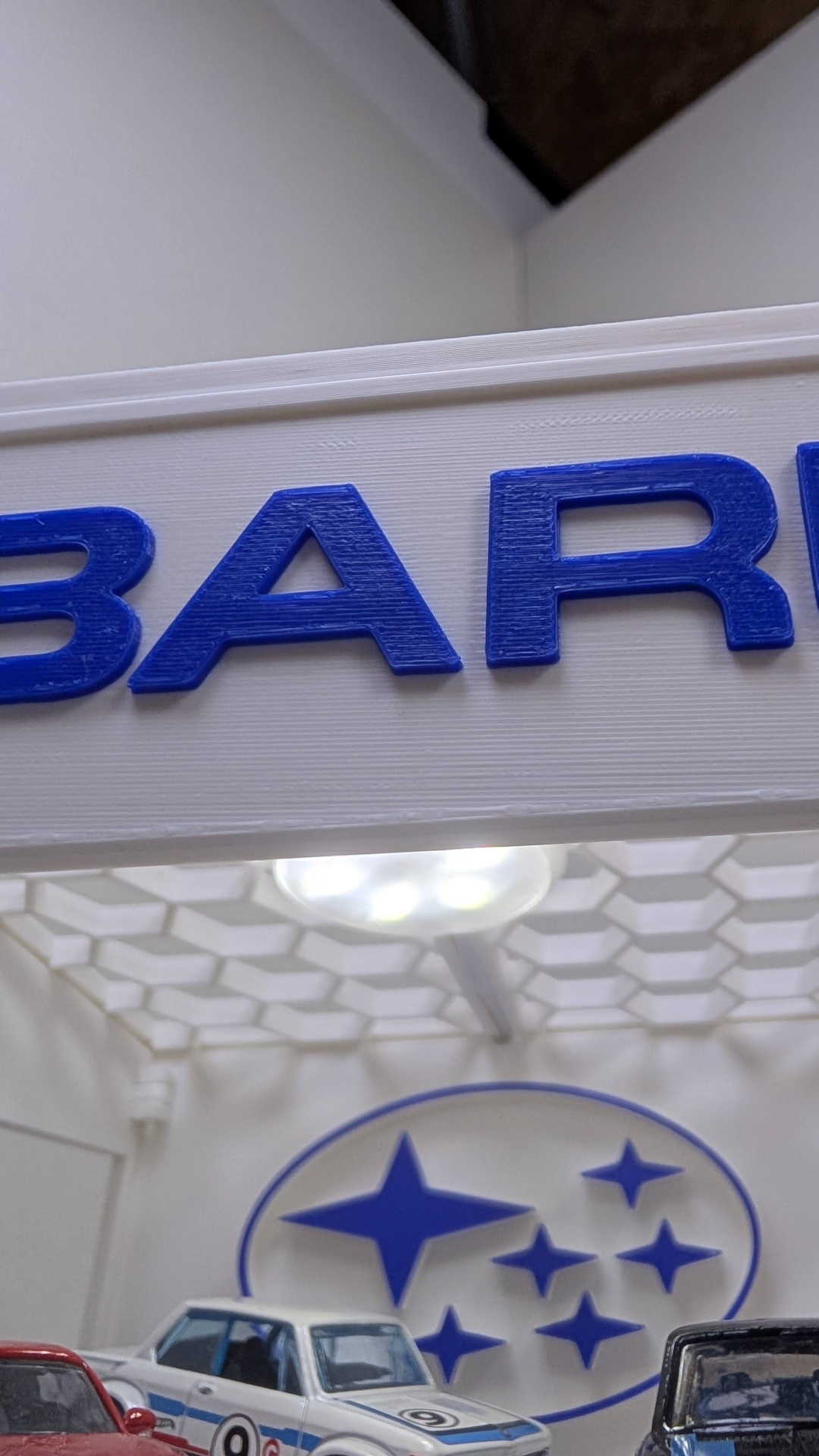 Miniaturas de carros com logotipo da Subaru azul em suporte branco