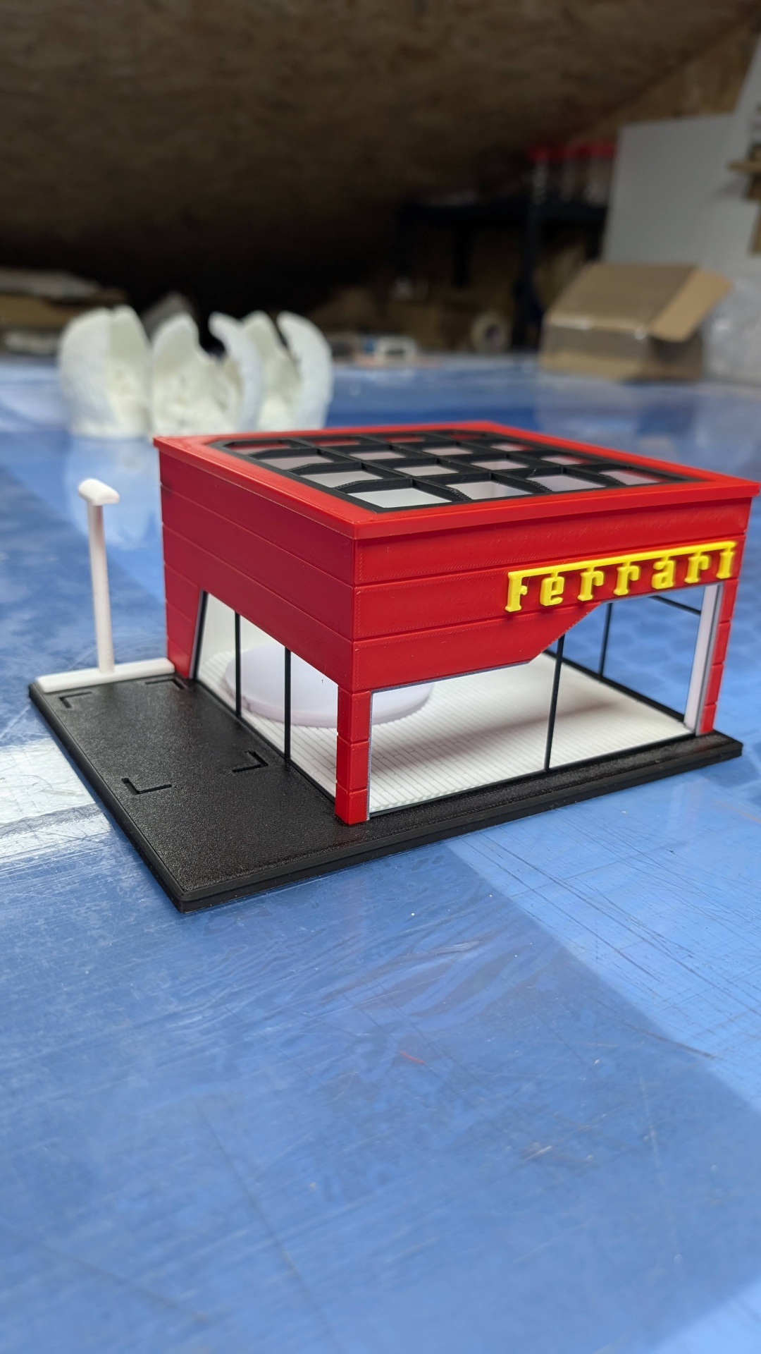 Miniatura de loja vermelha com letreiro FERRARI em amarelo e paredes de vidro