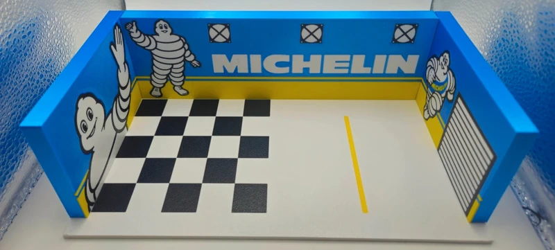 Miniatura de garagem de corrida com decoração Michelin e chão quadriculado