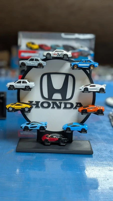 Suporte circular preto com logótipo Honda e miniaturas de carros coloridos à volta.