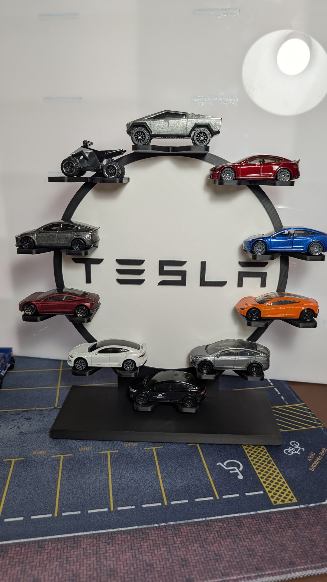 Miniaturas coloridas de carros Tesla em suporte circular com logotipo Tesla