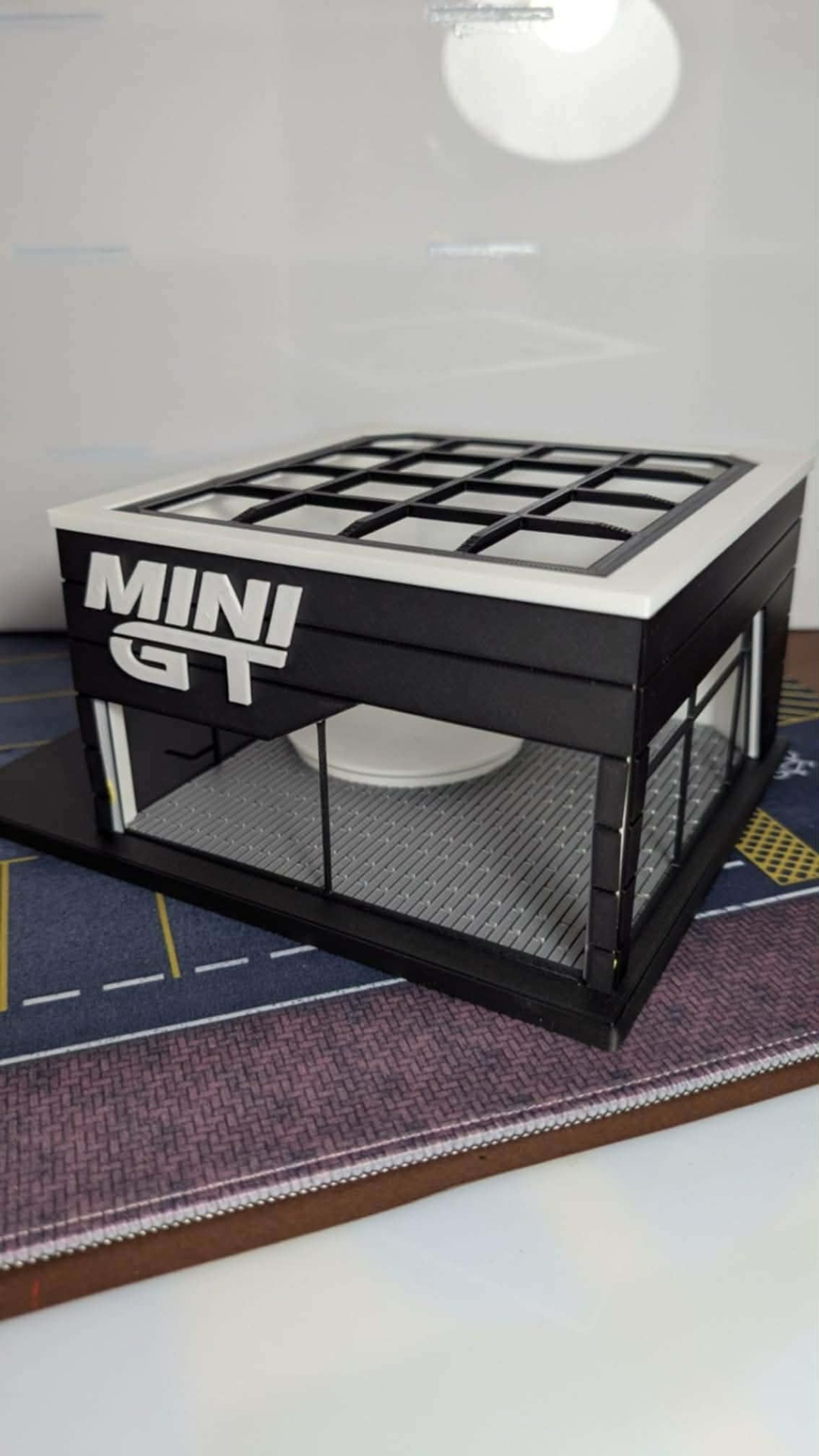 Modelo miniatura de edifício preto com janelas de vidro e logo MINI GT