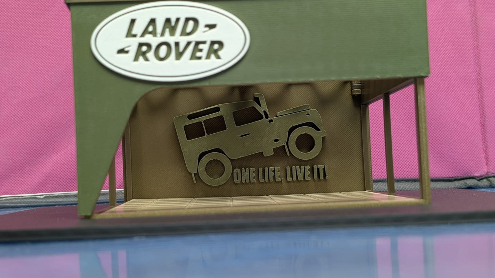 Exposição verde com logo Land Rover e recorte de jipe com texto motivacional.