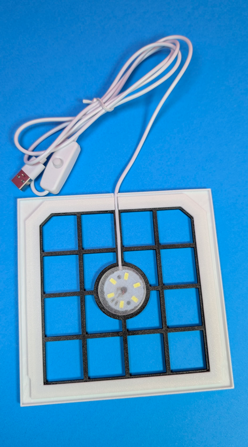 Placa quadrada branca com grelha preta, LED e cabo USB branco com interruptor