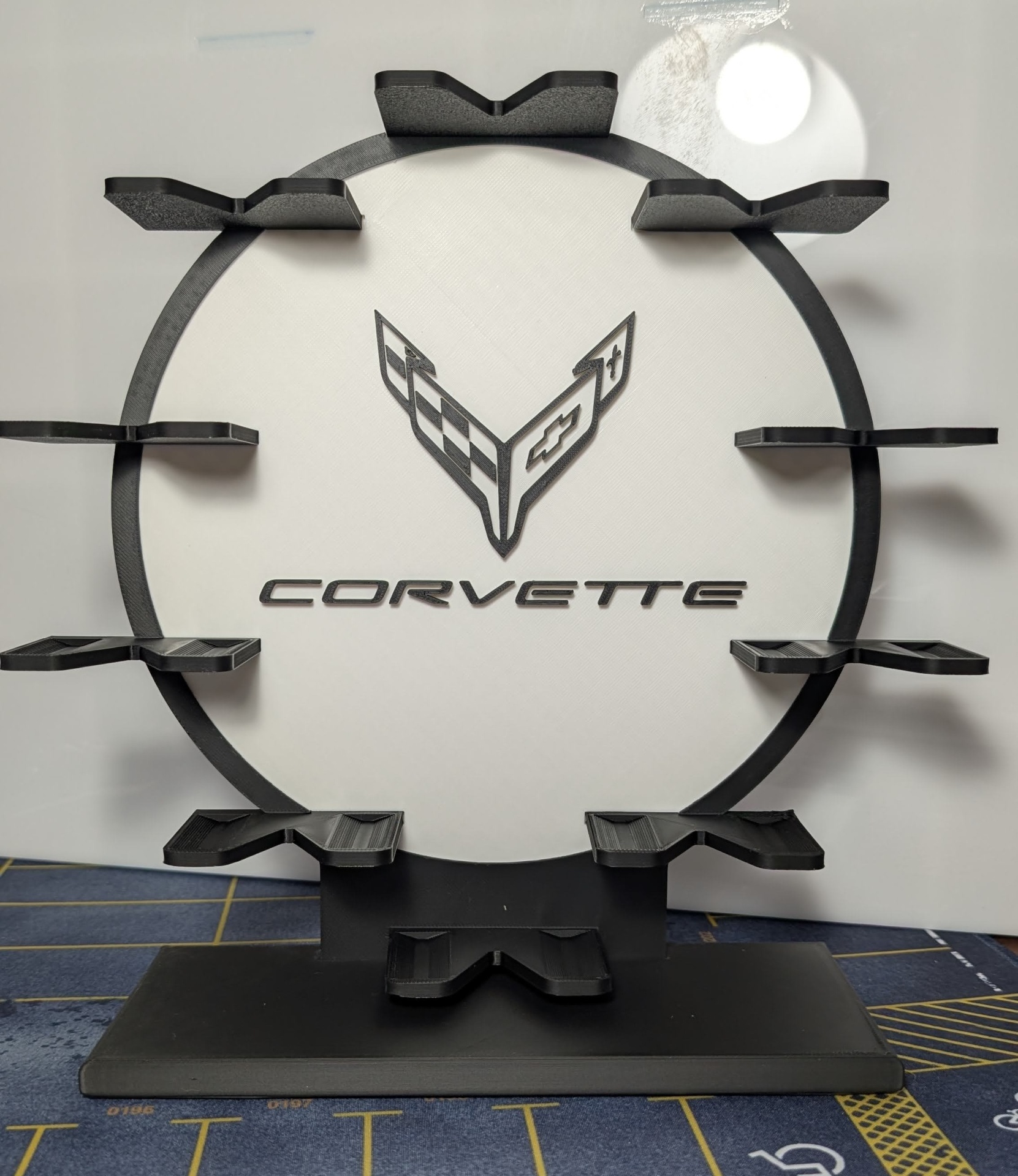 Expositor redondo preto e branco com logotipo e texto Corvette e prateleiras pretas.