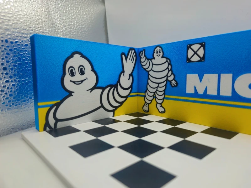 Suporte decorativo com ilustrações do boneco Michelin, fundo azul e amarelo, e padrão xadrez preto e branco na base.