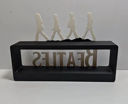 Escultura com figuras brancas e base preta com a palavra BEATLES