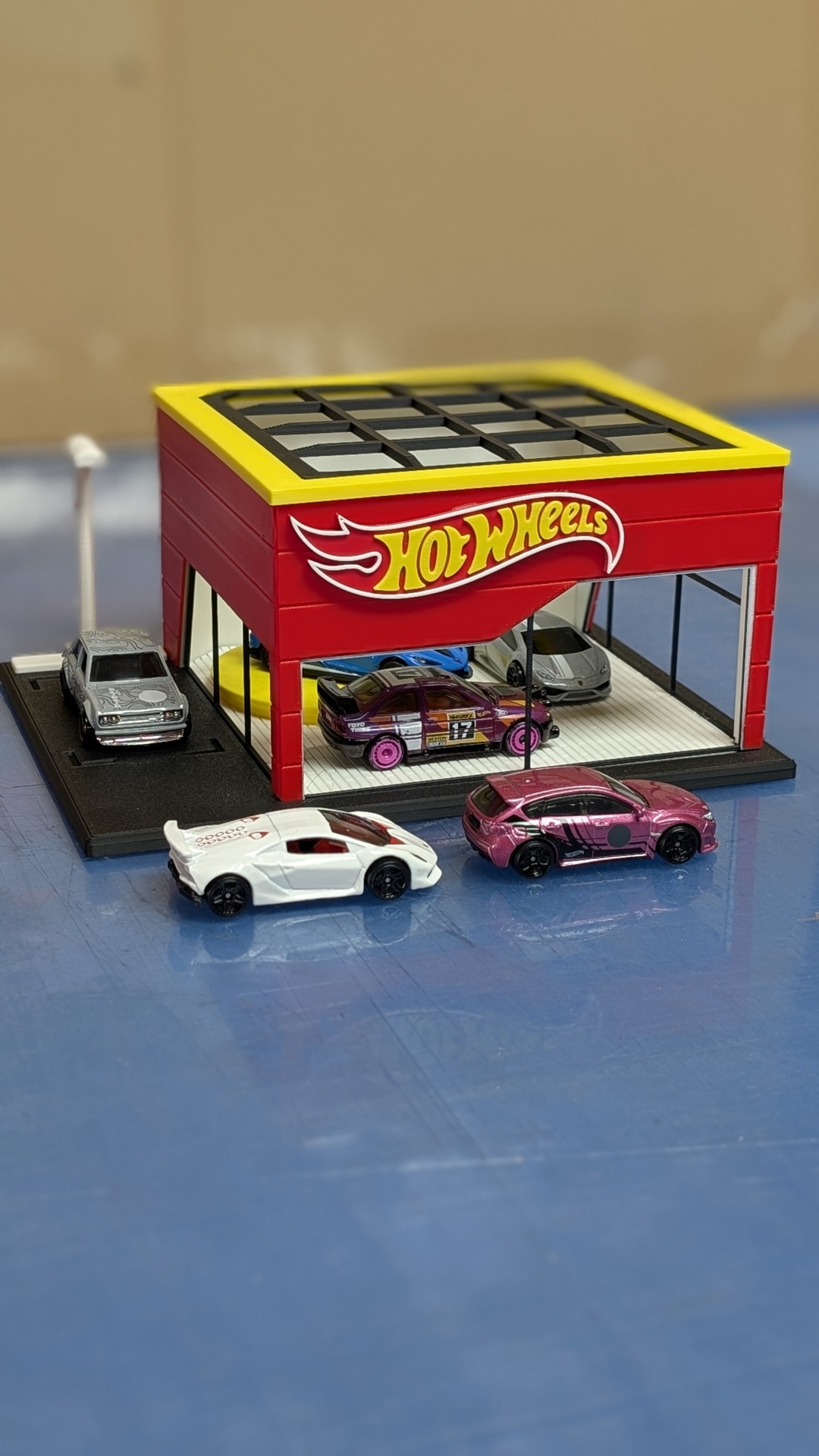 Carrinhos Hot Wheels em cenário com edifício vermelho e amarelo