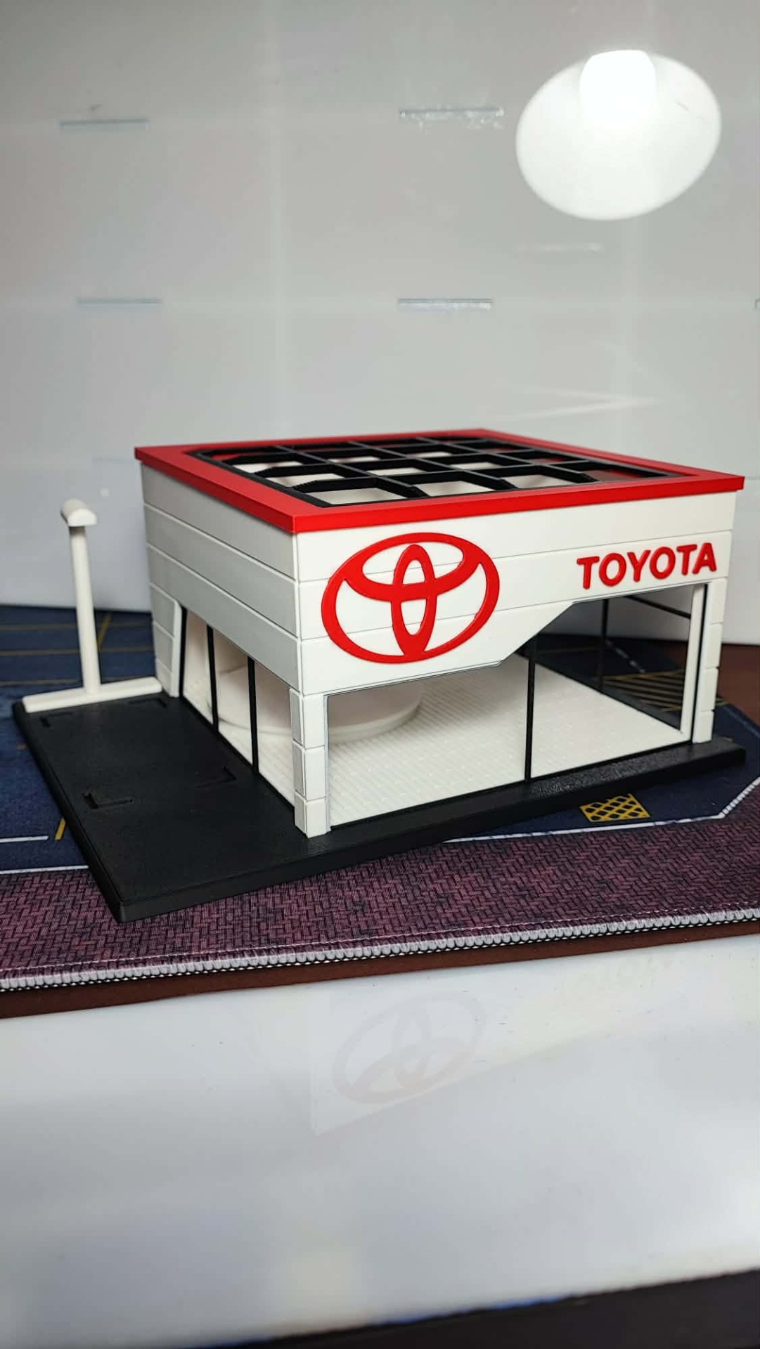 Miniatura de edifício Toyota branco com detalhes vermelhos e janelas pretas
