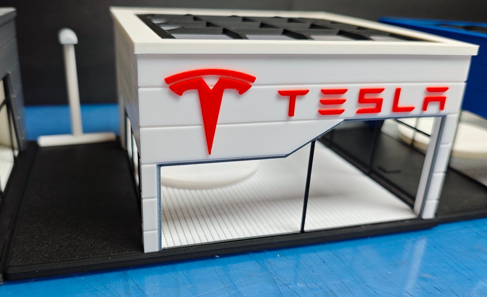 Miniatura de loja Tesla em plástico com logo vermelho e texto TESLA