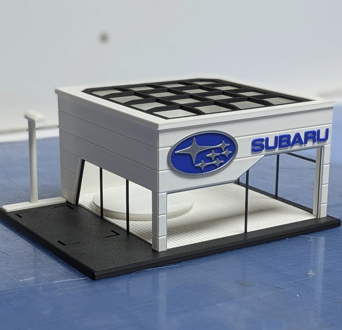 Maquete de loja Subaru com logotipo e texto em relevo azul