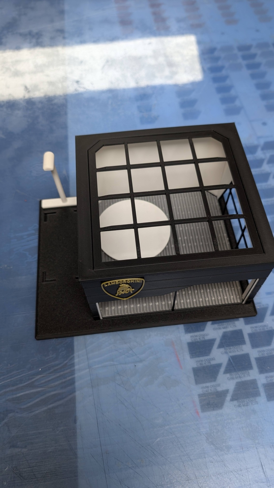 Miniatura de garagem Lamborghini com estrutura preta e vidro transparente.