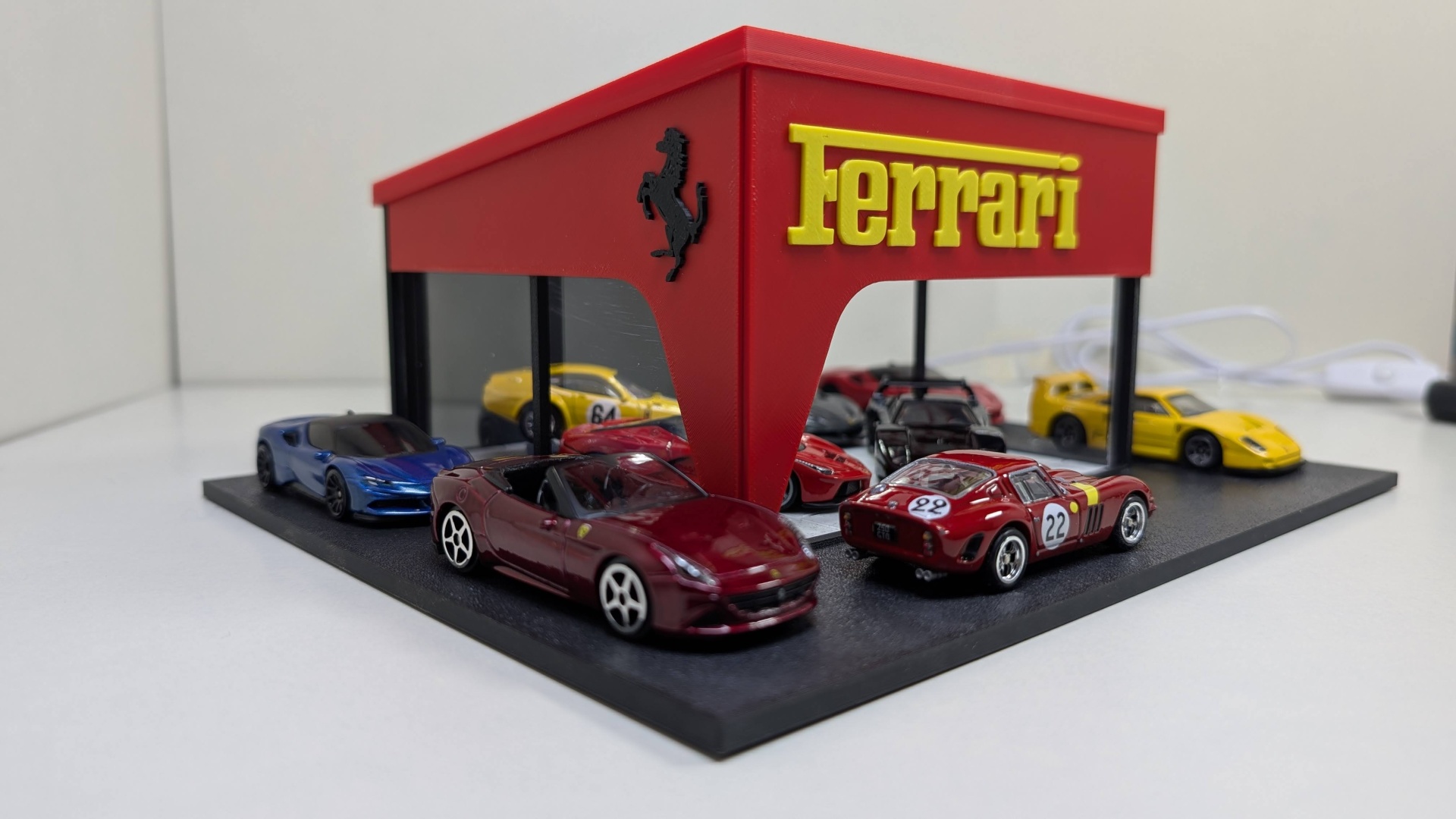 Miniaturas de carros Ferrari em suporte com logo Ferrari vermelho e amarelo