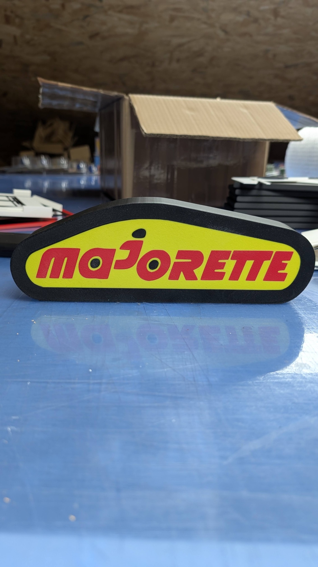 Bloco de plástico com a palavra majorette em vermelho sobre fundo amarelo e bordas pretas