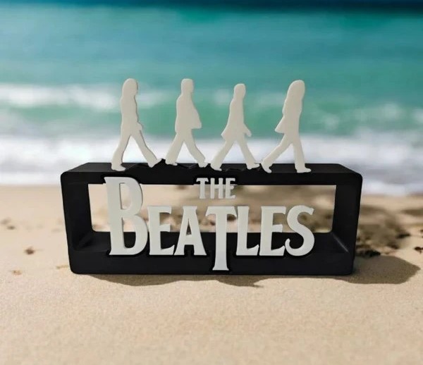 Estatueta decorativa preta com figura branca dos Beatles e texto THE BEATLES