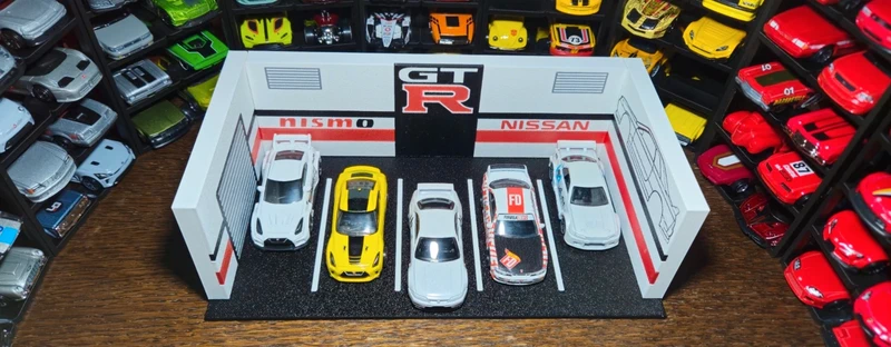 Miniaturas de carros Porsche e Nissan em garagem de exposição pequena