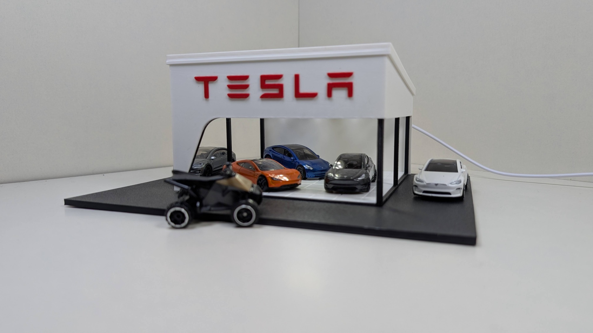 Modelo miniatura de concessionária Tesla com cinco carros miniatura coloridos