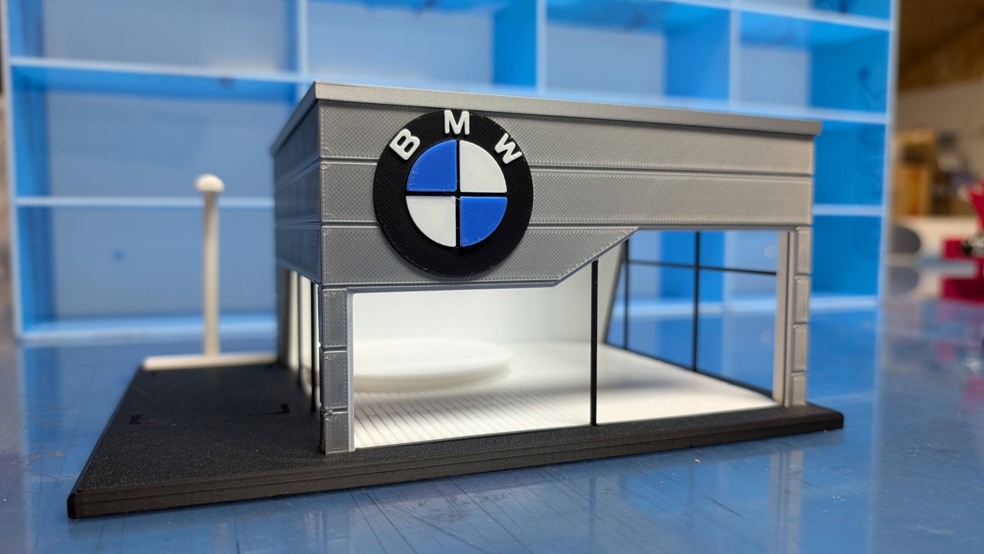 Miniatura de loja cinza com logo BMW e base preta