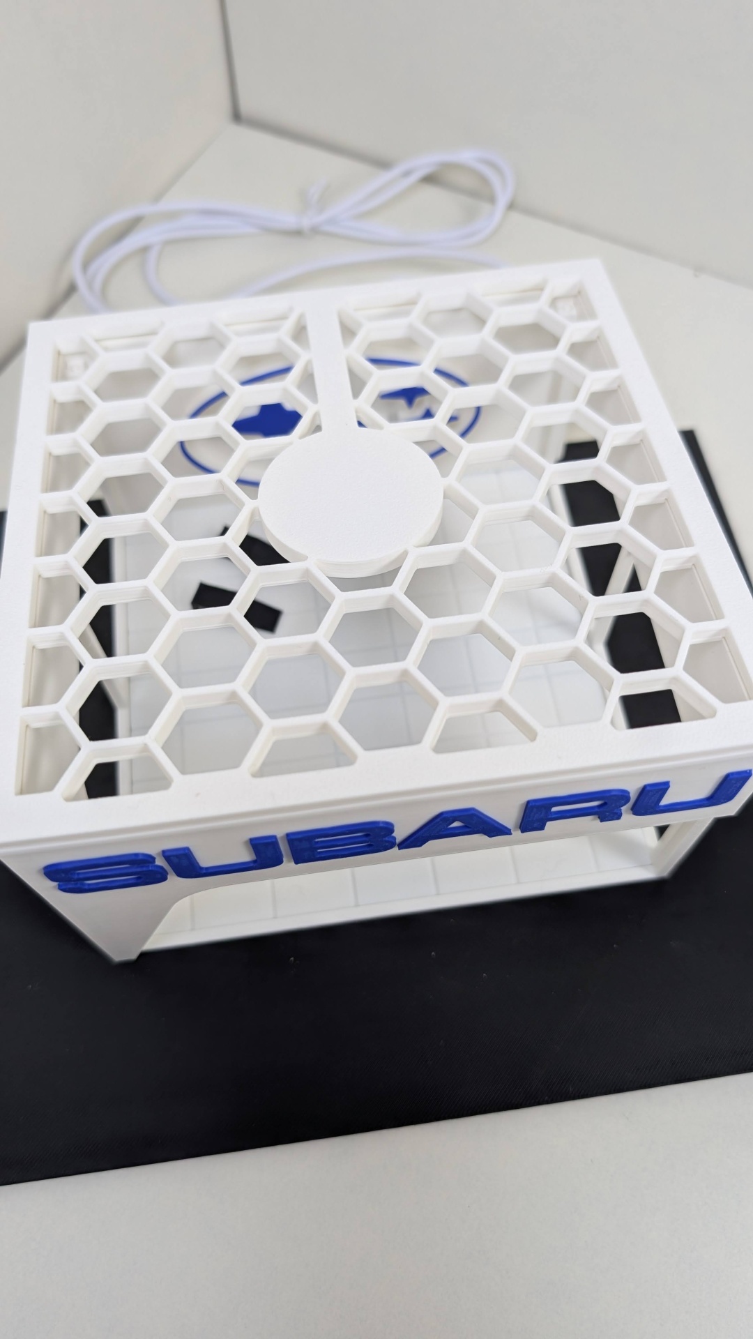 Ventoinha branca com padrão hexagonal e logótipo SUBARU azul na lateral