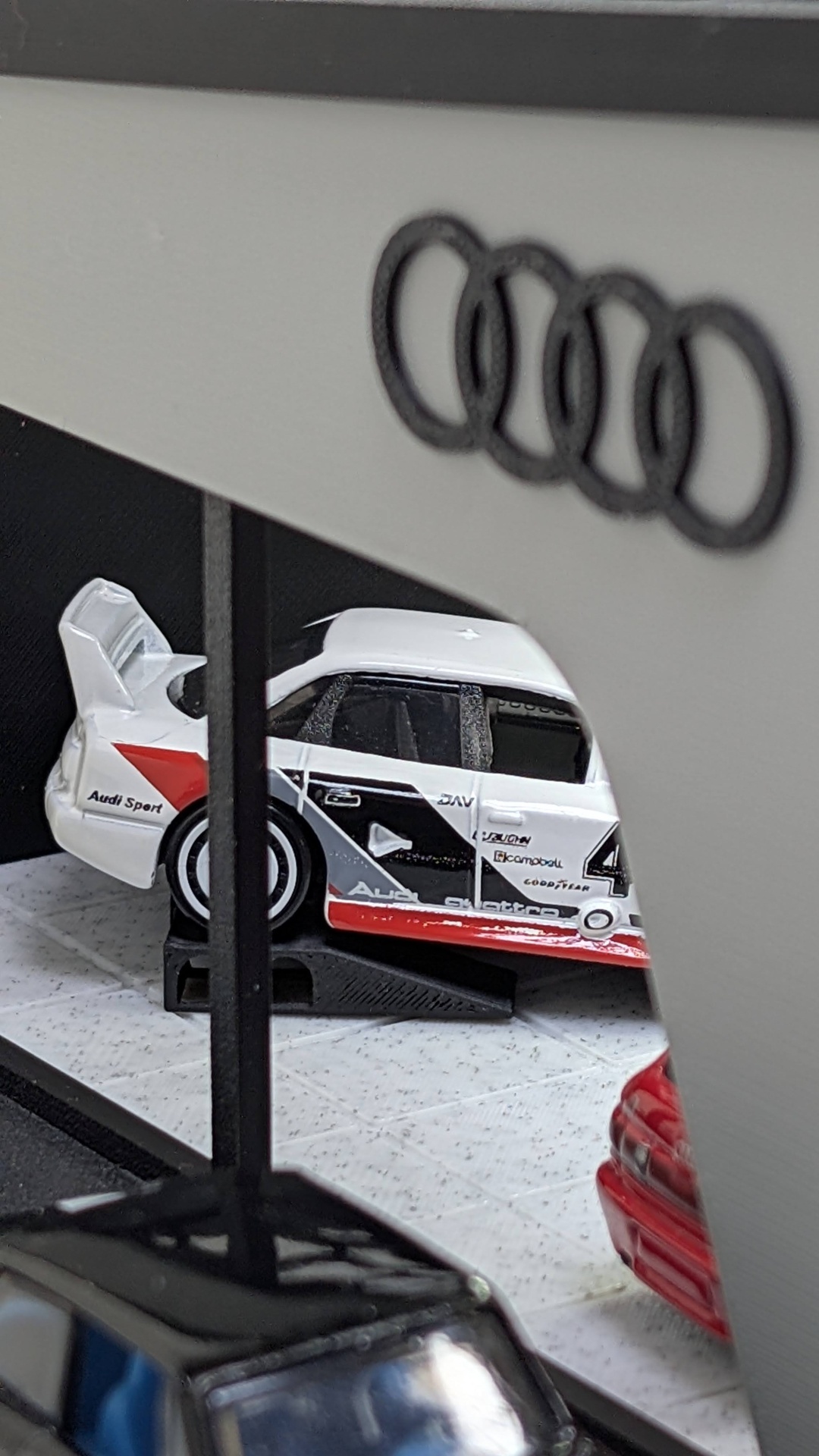 Miniatura de carro de corrida Audi branco, preto e vermelho com logotipos numa exibição