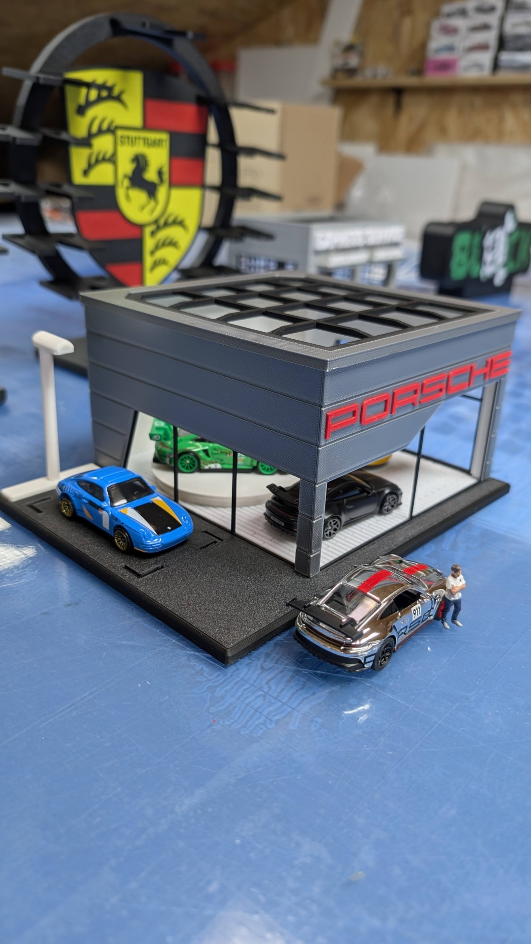 Maqueta de concessionária Porsche com carros e figura miniatura