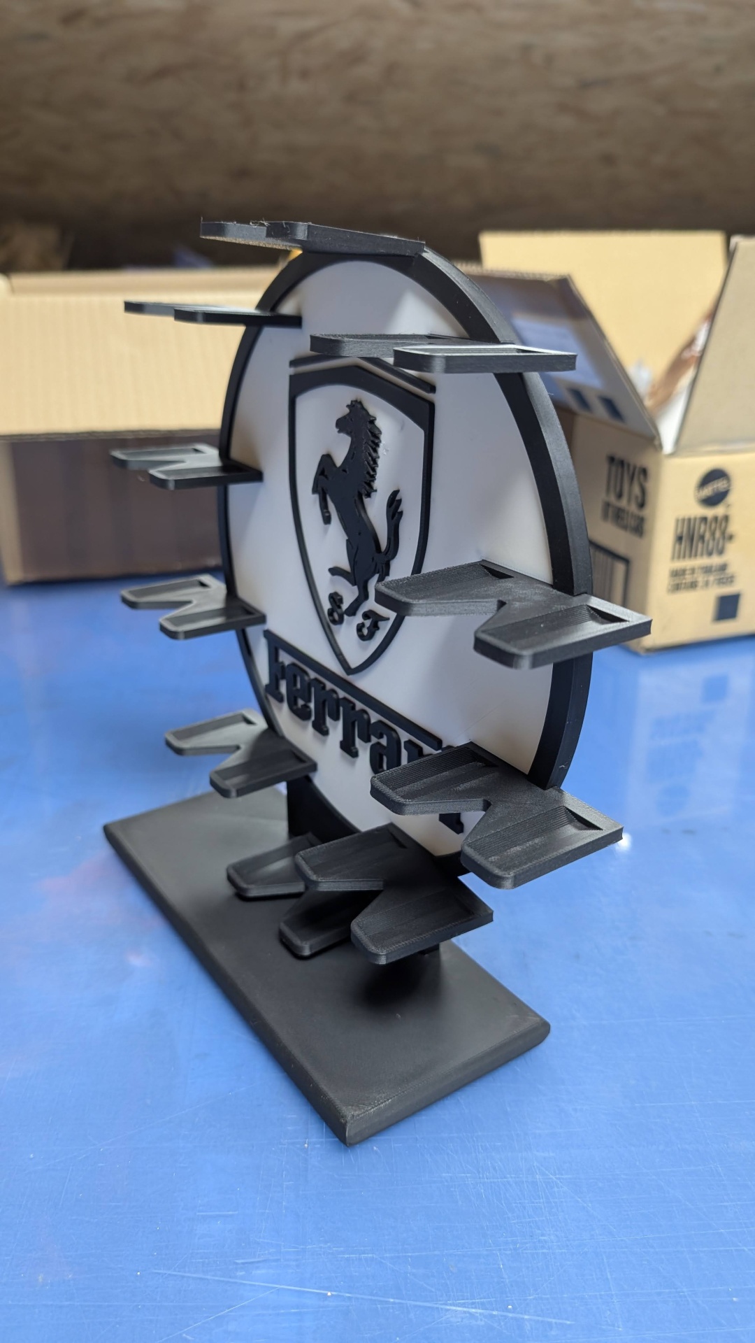 Expositor de plástico preto com logotipo Ferrari em branco e preto e plataformas para suporte