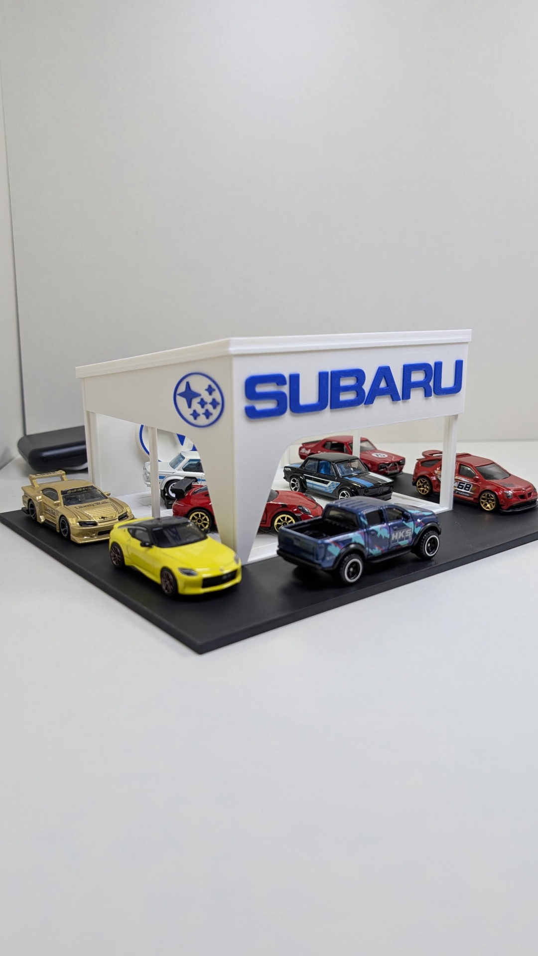 Parque de estacionamento Subaru com miniaturas de carros de coleção coloridos.