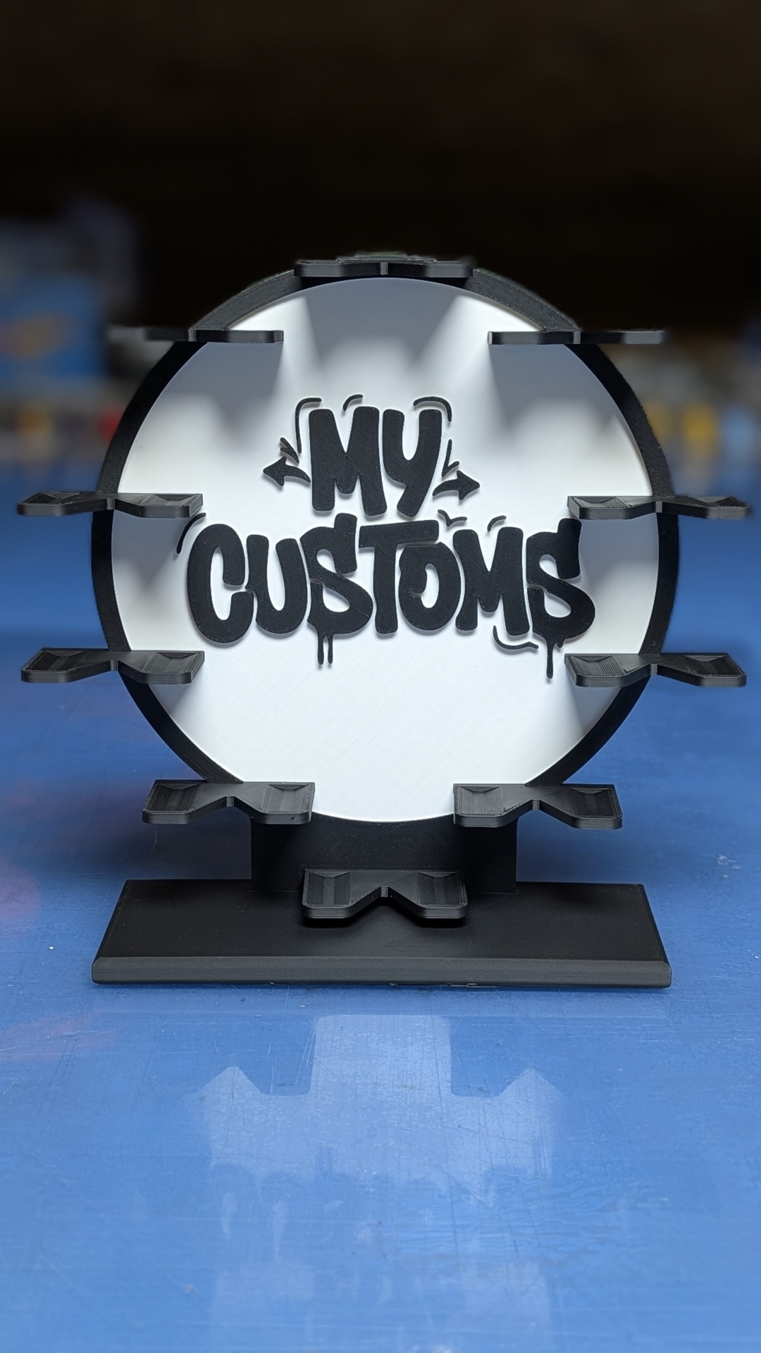 Suporte preto e branco com texto MY CUSTOMS e prateleiras pequenas para exposição de objetos
