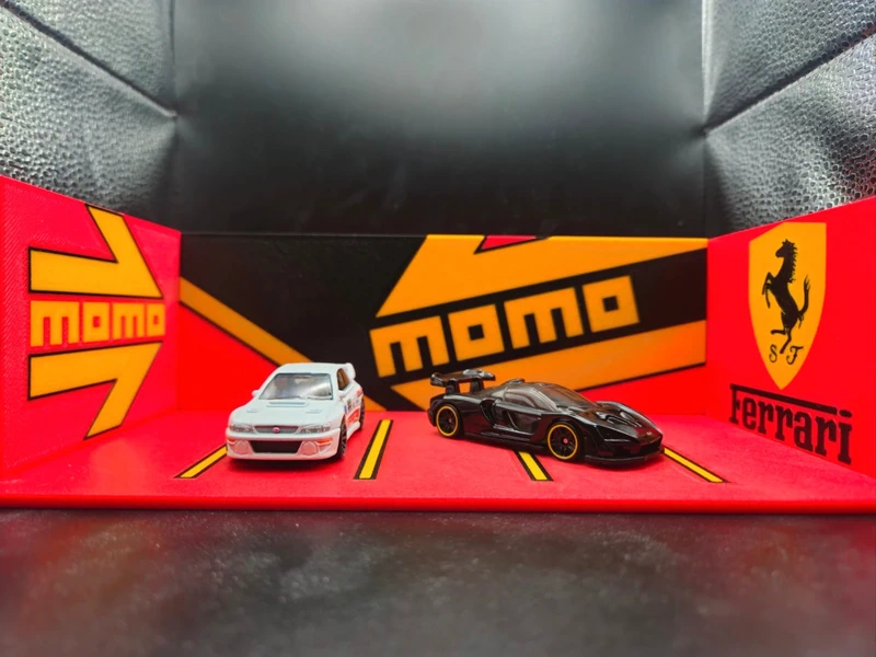 Miniaturas de carros branco e preto junto a logos MOMO e Ferrari