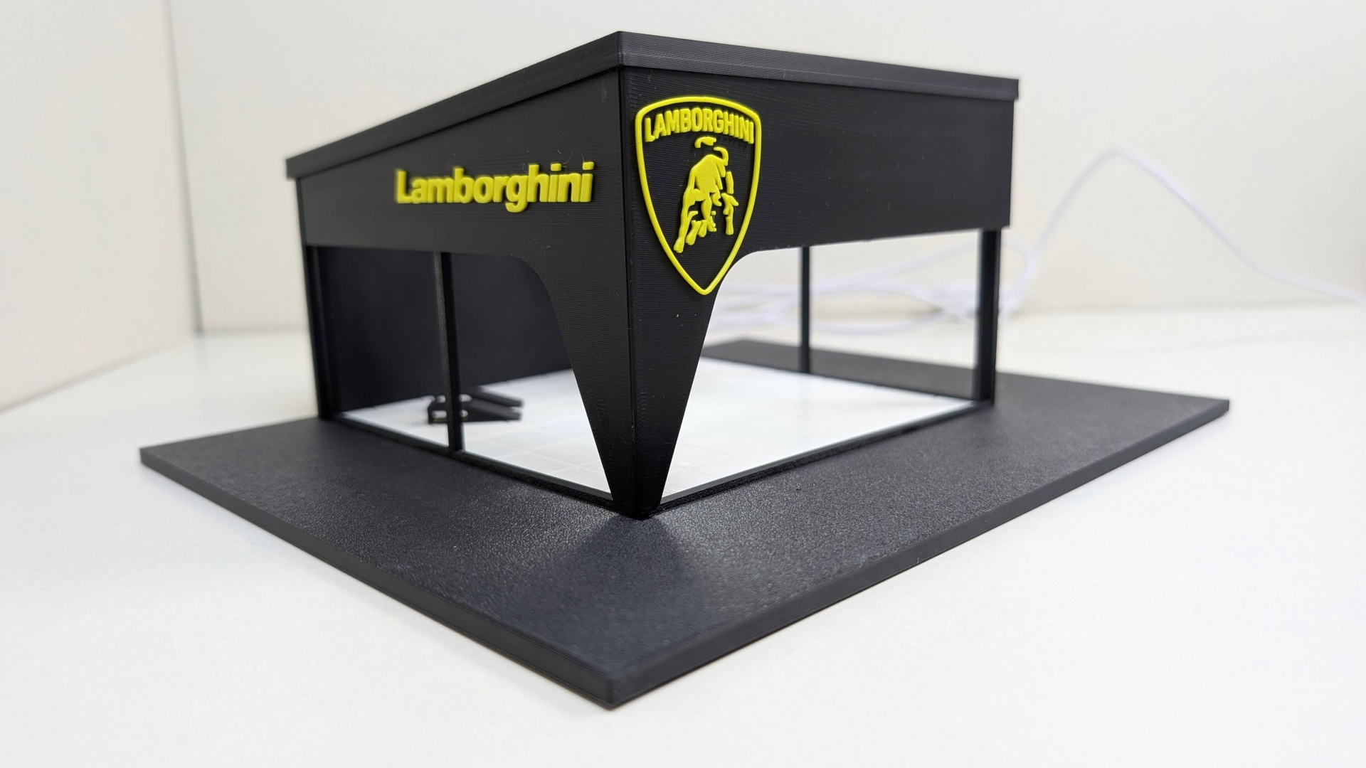 Modelo em miniatura de edifício preto com logótipo e nome Lamborghini em amarelo numa base preta