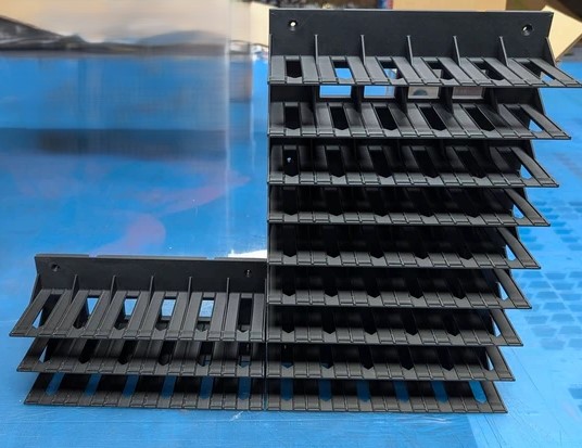 Suporte modular de plástico preto com prateleiras ajustáveis sobre superfície azul