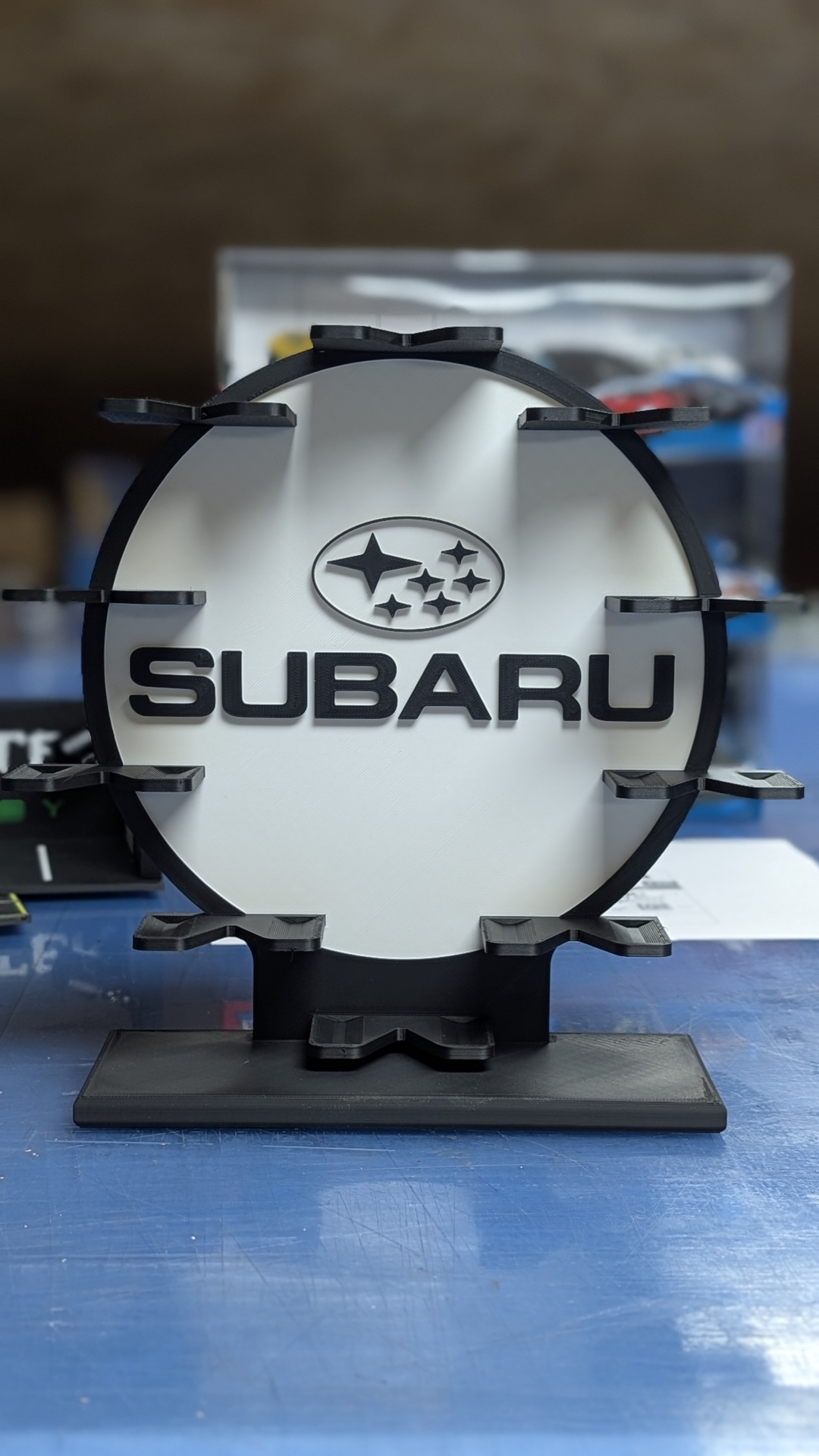 Expositor branco e preto com logótipo SUBARU em plástico.