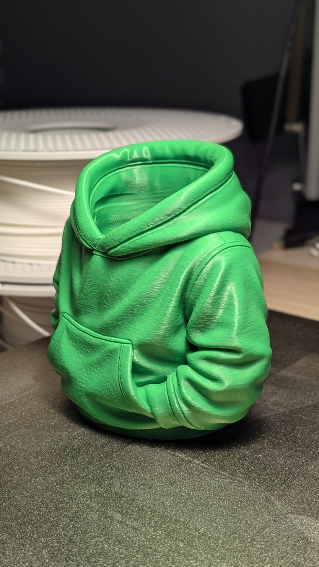 Miniatura de camisola hoodie verde sem cabeça nem mãos sobre superfície escura