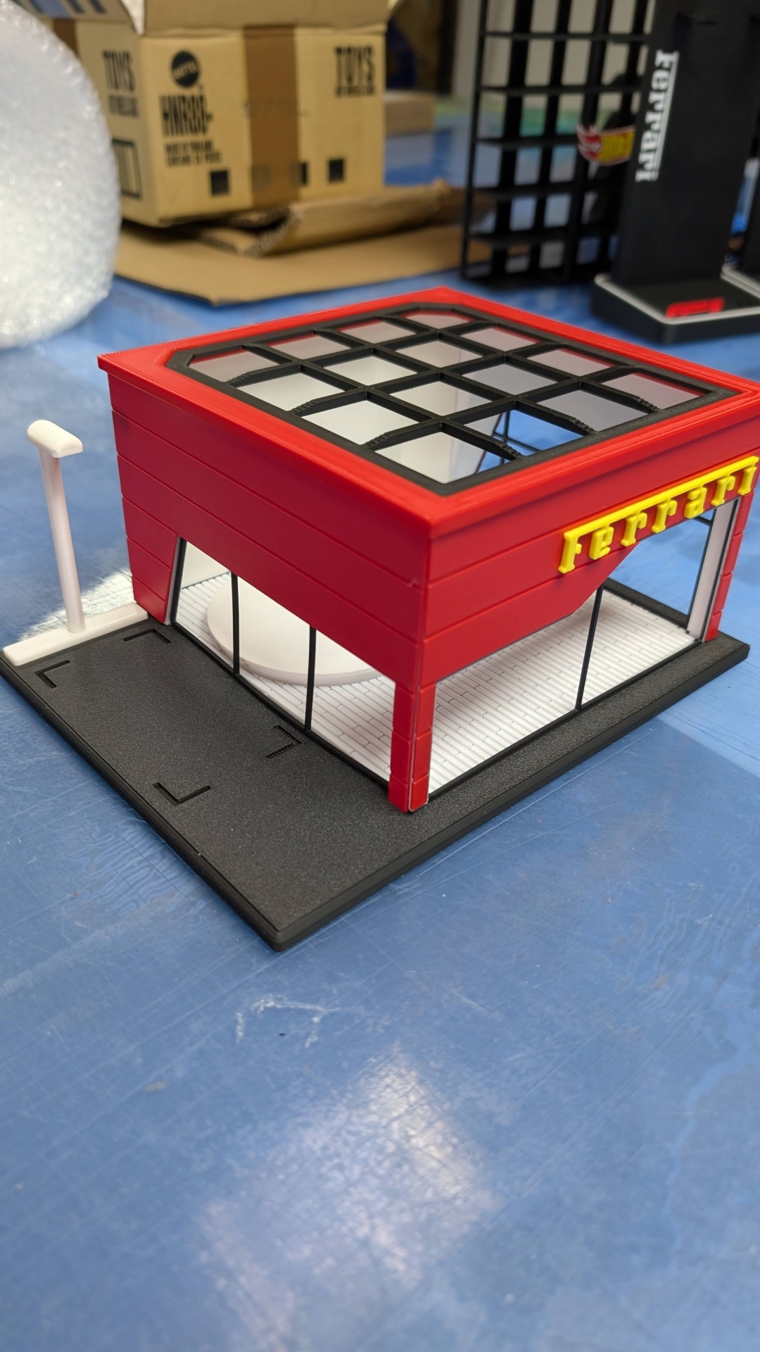 Miniatura de prédio vermelho com placa Ferrari e base preta e branca