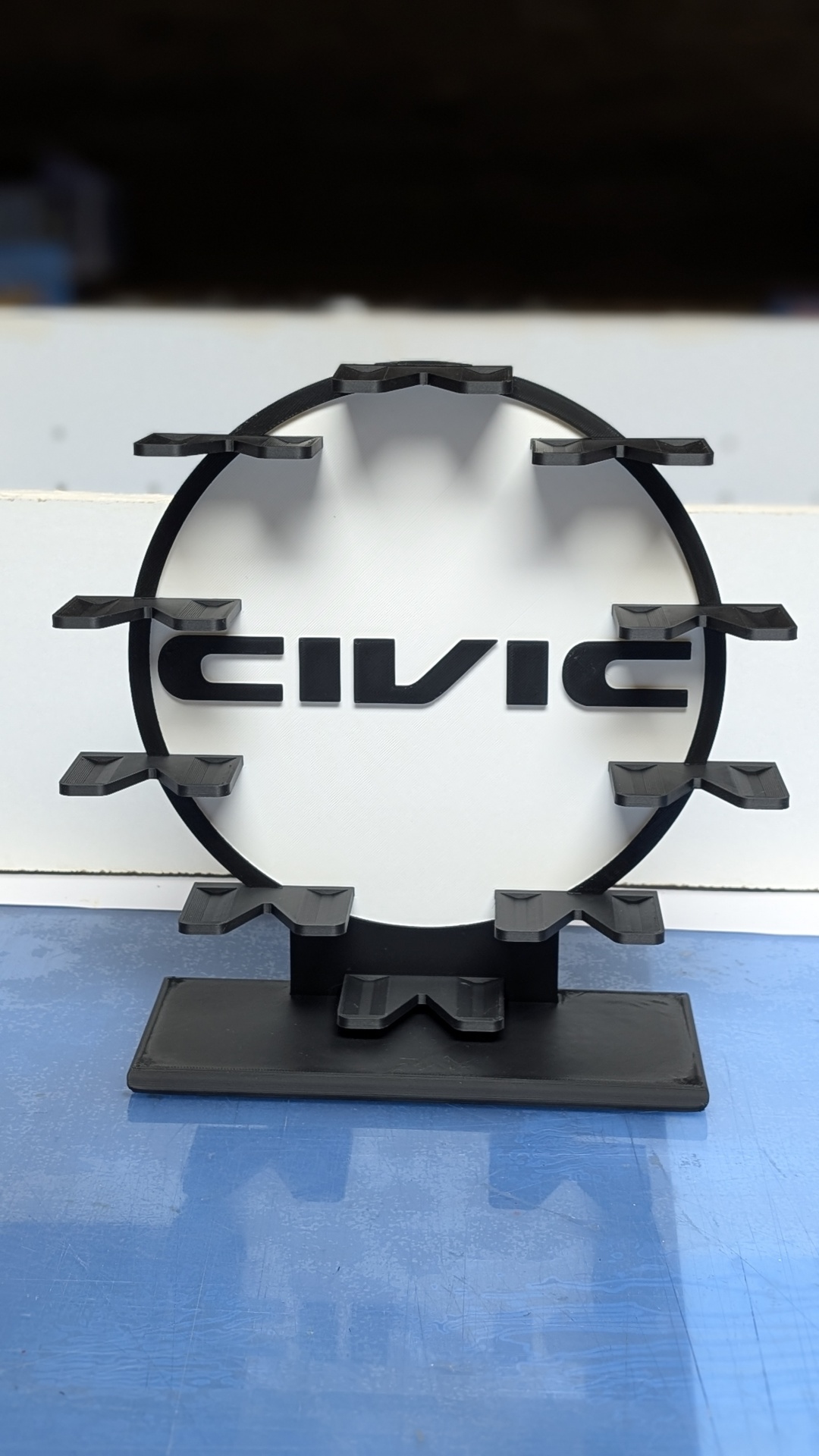 Suporte preto com presilhas e texto Civic em fundo branco