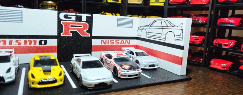 Miniaturas de carros de corrida Nissan GT-R em caixa decorativa branca com texto e desenhos.