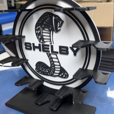Suporte de exposição negro e branco com logótipo Shelby e padrão de cobra