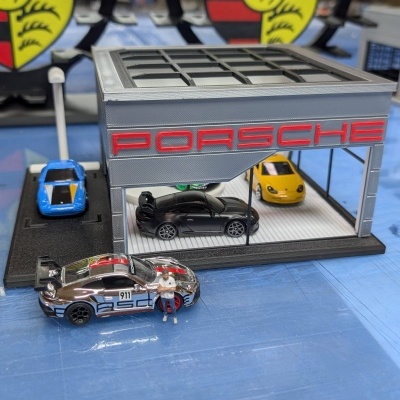 Miniatura de garagem e carros Porsche com logótipos Porsche Stuttgart em fundo