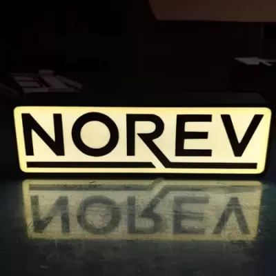 Placa luminosa rectangular com texto NOREV em branco e preto