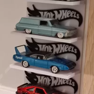 Quatro miniaturas de carros Hot Wheels em prateleiras brancas com logo Hot Wheels ao fundo