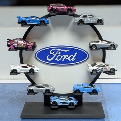 Conjunto de miniaturas de carros coloridos em suporte circular com logótipo Ford ao centro.