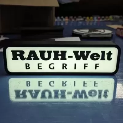 Placa iluminada RAUH-Welt BEGRIFF sobre superfície azul refletora